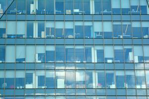 vidro construção com transparente fachada do a construção e azul céu. estrutural vidro parede refletindo azul céu. abstrato moderno arquitetura fragmento. contemporâneo arquitetônico fundo. foto