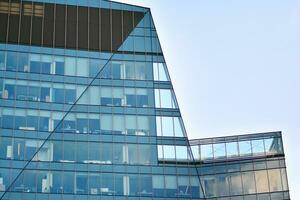 vidro construção com transparente fachada do a construção e azul céu. estrutural vidro parede refletindo azul céu. abstrato moderno arquitetura fragmento. contemporâneo arquitetônico fundo. foto