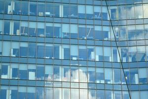 vidro construção com transparente fachada do a construção e azul céu. estrutural vidro parede refletindo azul céu. abstrato moderno arquitetura fragmento. contemporâneo arquitetônico fundo. foto