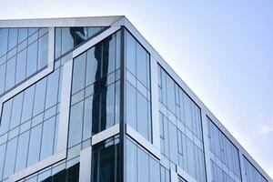 vidro construção com transparente fachada do a construção e azul céu. estrutural vidro parede refletindo azul céu. abstrato moderno arquitetura fragmento. contemporâneo arquitetônico fundo. foto