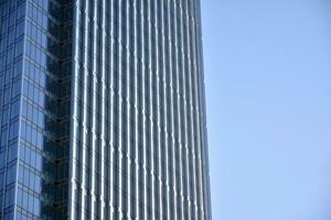 vidro construção com transparente fachada do a construção e azul céu. estrutural vidro parede refletindo azul céu. abstrato moderno arquitetura fragmento. contemporâneo arquitetônico fundo. foto