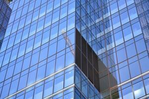 vidro construção com transparente fachada do a construção e azul céu. estrutural vidro parede refletindo azul céu. abstrato moderno arquitetura fragmento. contemporâneo arquitetônico fundo. foto