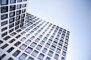 moderno escritório construção dentro a cidade com janelas e aço e alumínio painéis muro. contemporâneo comercial arquitetura, vertical convergindo geométrico linhas. foto