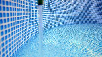 água fluindo a partir de a mangueira para dentro a piscina enchimento. a dentro do a natação piscina. foto