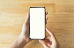 topo Visão do mão segurando Preto Smartphone com em branco tela em madeira fundo. foto