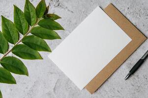 um cartão em branco com envelope, caneta e folha é colocado no fundo branco foto
