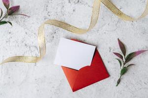 um cartão em branco com um envelope vermelho e uma folha é colocado em um fundo branco foto