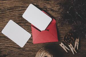 dois cartões em branco com envelope vermelho e prendedor de roupa são colocados na madeira. foto