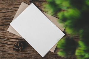 um cartão em branco é colocado em um envelope e uma folha com fundo de madeira