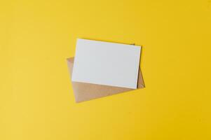 um cartão em branco com envelope é colocado em fundo amarelo foto