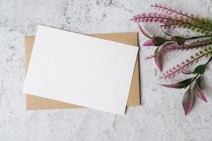um cartão em branco com um envelope e uma flor é colocado em um fundo branco foto