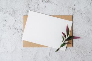 um cartão em branco com um envelope e uma flor é colocado em um fundo branco foto