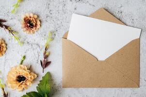 um cartão em branco com um envelope e uma flor é colocado em um fundo branco foto