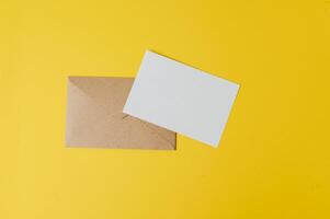 um cartão em branco com envelope é colocado em fundo amarelo foto