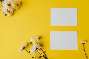 dois cartões em branco com flores são colocados em fundo amarelo foto