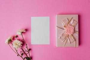 caixa de presente rosa, flor e cartão em branco sobre fundo rosa foto