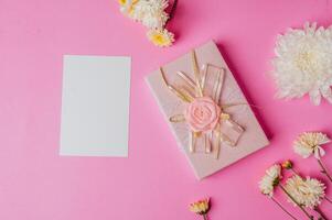 caixa de presente rosa, flor e cartão em branco sobre fundo rosa foto