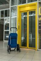 uma azul saco em rodas carrinhos Próximo para uma amarelo elevador. azul amarelo. compras carrinhos. foto