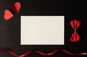 papel branco e papel de coração vermelho colados em um fundo preto. foto