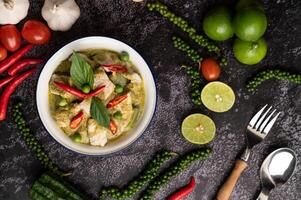 curry de porco verde em uma tigela branca com especiarias em um cimento preto foto