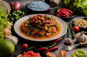 curry vermelho com carne de porco em um prato branco foto