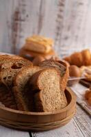 fatias de pão colocadas em uma placa de madeira sobre uma mesa de madeira branca. foto