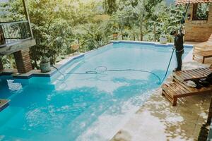 piscina manutenção e limpeza com vácuo sucção mangueira. trabalhador limpeza uma lindo natação piscina com vácuo sucção mangueira foto