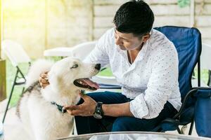 cara sentado jogando com dele rouco cachorro. jovem homem sentado acariciando dele cachorro dentro a quintal. conceito do pessoa acariciando dele rouco cachorro foto