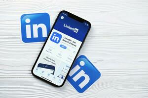 Carcóvia, Ucrânia - marcha 5, 2021 linkedin ícone e inscrição a partir de aplicativo loja em Iphone 12 pró exibição tela em branco mesa foto