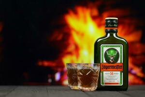 kyiv, ucrânia - 4 de maio de 2022 jagermeister garrafa de álcool original na mesa de madeira com lareira vermelha foto