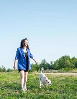 jovem mulher atraente passeando com o cachorro no parque em dia de verão foto
