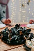 cru mexilhões em uma Preto prato às uma cozinhando aula. mestre classe em frutos do mar. cozinhando mexilhões. foto