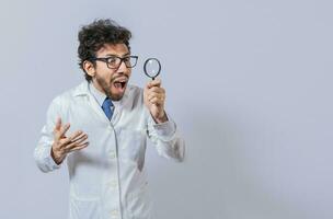 surpreso cientista observando com uma ampliação vidro para a lado. cientista segurando uma ampliação vidro olhando para a lado, homem dentro uma branco casaco com uma ampliação vidro olhando propaganda foto