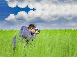 homem levando cenário com Câmera dentro a campo, fotógrafo dentro a campo levando uma foto, latino homem dentro uma verde campo levando uma cenário foto