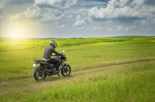 motociclista homem em uma país estrada, jovem homem em dele motocicleta viajando através a campo com cópia de espaço, homem equitação motocicleta dentro a campo foto