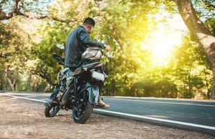 homem sentado em dele motocicleta às a lado do a estrada. motociclista sentado em dele motocicleta às a lado do a estrada foto