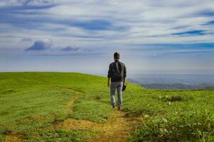 uma mochileiro caminhando em uma Colina com azul céu e cópia de espaço, homem mochilão em uma Colina e azul céu fundo com cópia de espaço, bem sucedido homem conceito. foto