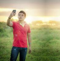 jovem homem levando uma foto, jovem homem levando selfie dentro a campo, jovem homem dentro a campo levando uma cenário foto