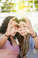 fechar acima do dois meninas fazer uma coração forma, dois amigos juntos formando uma coração, amor mãos placa foto