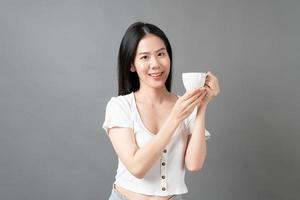 jovem mulher asiática com um rosto feliz e uma mão segurando uma xícara de café foto