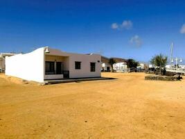 uma branco casa em uma arenoso de praia com uma barco dentro a fundo foto