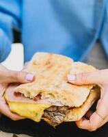 uma jovem pessoa desfrutando uma carne sanduíche foto