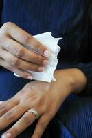 mulheres desinfecção dela mãos com uma molhado limpar. foto