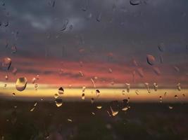 gotas de chuva no vidro luz amarela vermelha foto