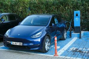 Istambul, Peru - novembro 5, 2023, Sombrio azul Tesla modelo y é cobrando às ao ar livre dentro uma cobrando estação conhecido Como esarj dentro Peru foto