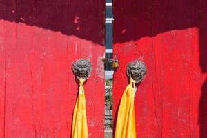 porta de madeira vermelha com argola de metal ao redor do templo em qinghai china. foto