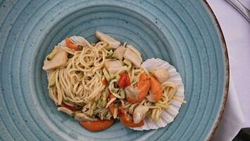 italiano espaguete com uma peixe molho vestir em uma prato às uma frutos do mar restaurante foto