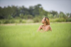 jovem sentada se sentir bem no campo de grama. foto