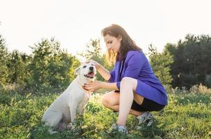 jovem mulher atraente abraçando seu cachorro no parque ao pôr do sol foto