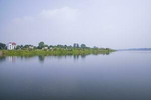 reflexão do árvores dentro a lago água contra a azul céu panorama campo dentro Bangladesh foto